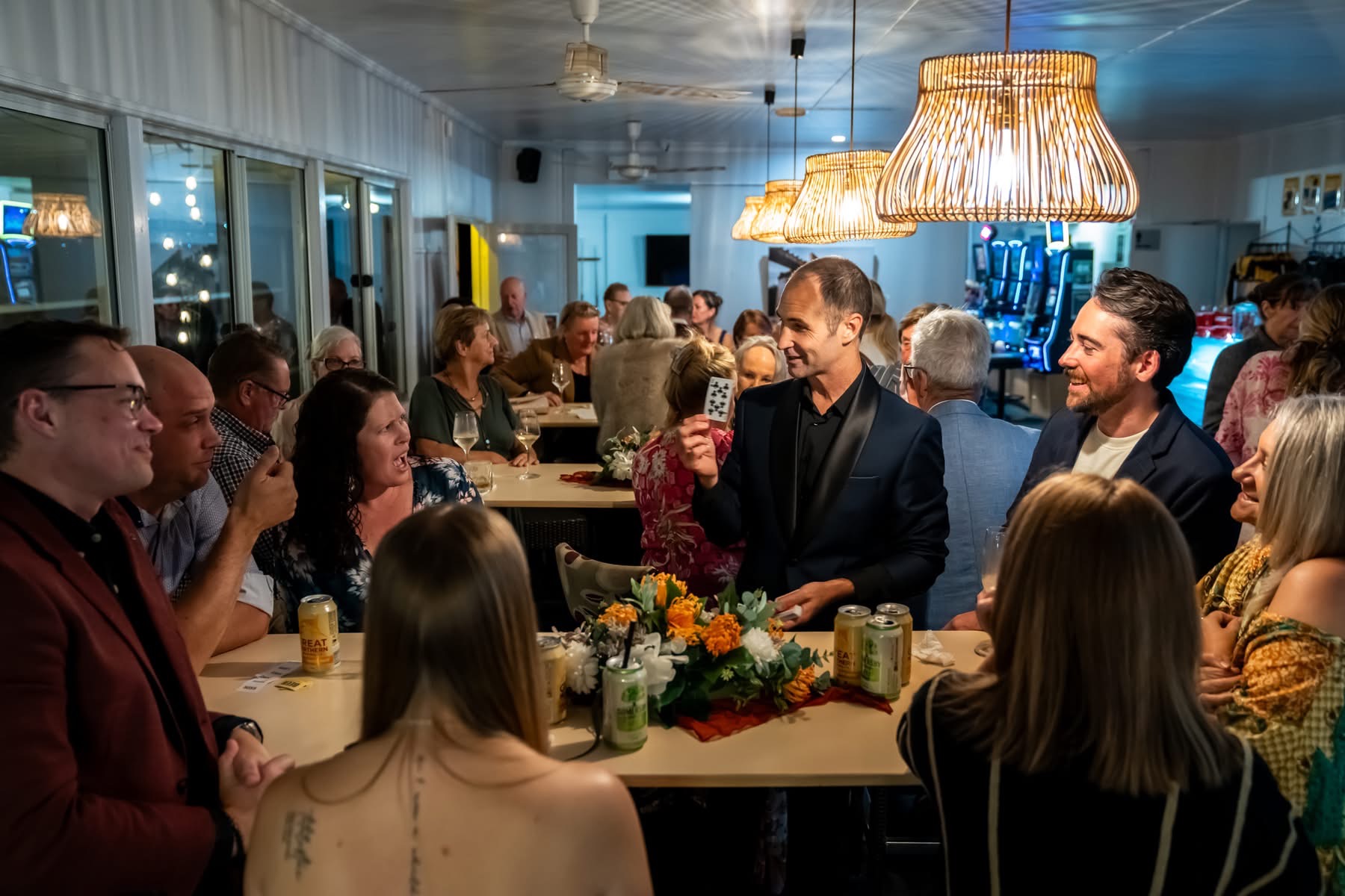 Craig sharing close-up card magic with guests gathered around a table